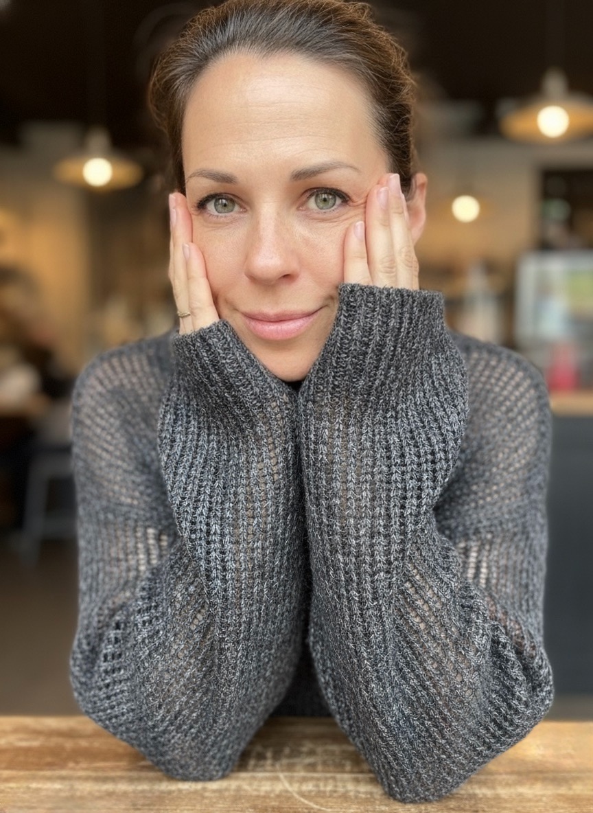 Pauline am Tisch, das Kinn in die Hände gestützt